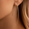 Gold earring worn by a person with blonde hair.