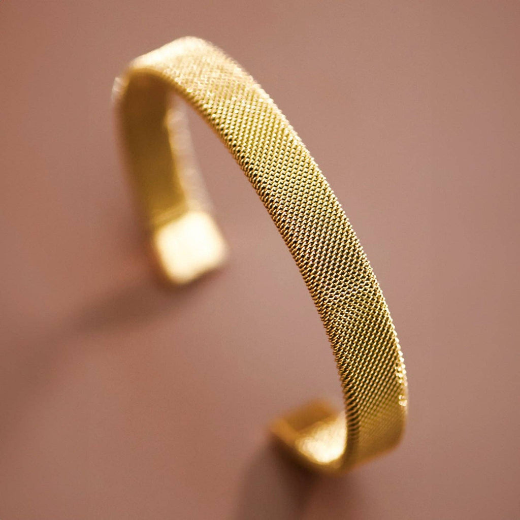 Gold mesh bracelet on a blurred background