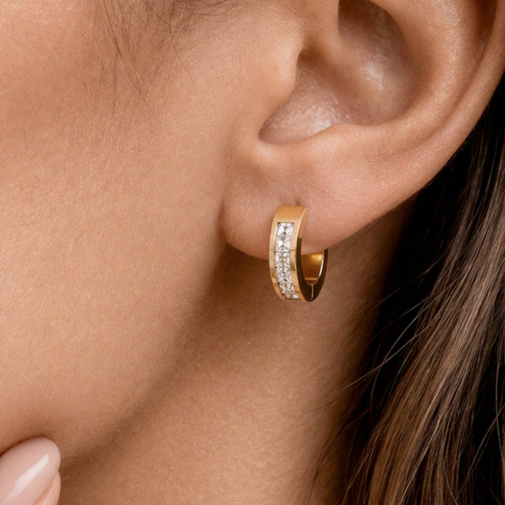 Gold hoop earring with embedded diamonds worn by a person