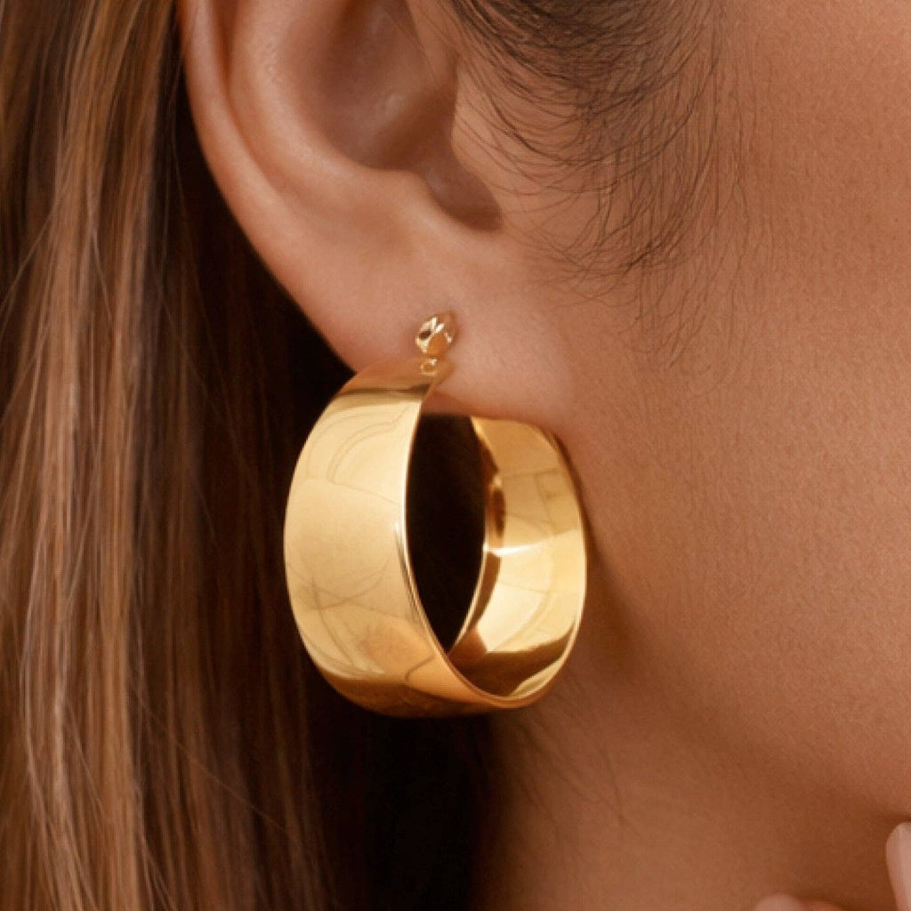 Gold hoop earring worn by a person with brown hair.