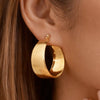 Gold hoop earring worn by a person with brown hair.