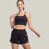 Woman wearing a black sports bra and shorts on a light gray background with a 'Recycled Polyester' label.