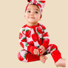 Baby wearing a strawberry-themed outfit with a matching headband on a white background