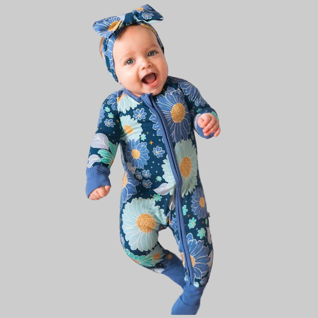 Baby wearing a floral onesie and headband on a white background