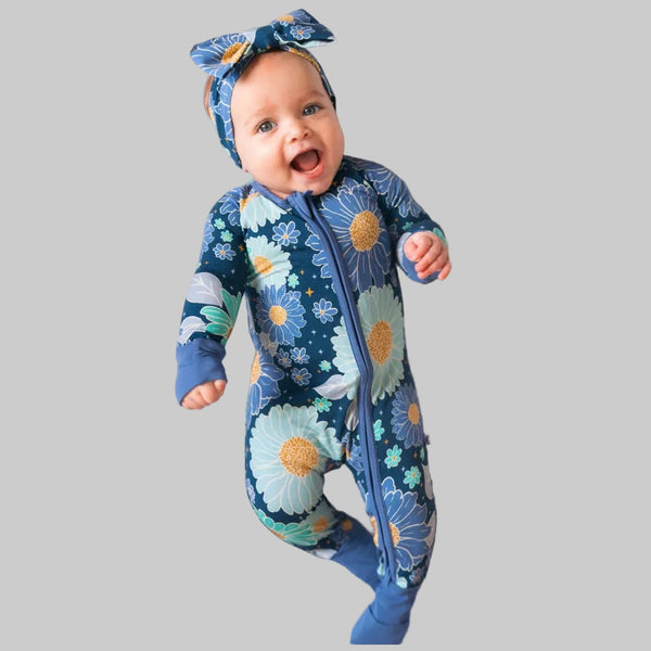 Baby wearing a floral onesie and headband on a white background