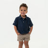 Child wearing a navy patterned shirt and beige shorts on a white background