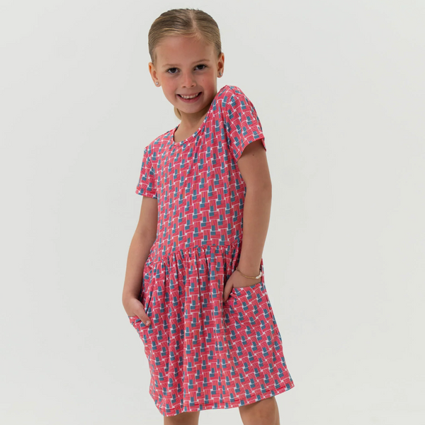 Young girl wearing a red and blue patterned dress on a white background