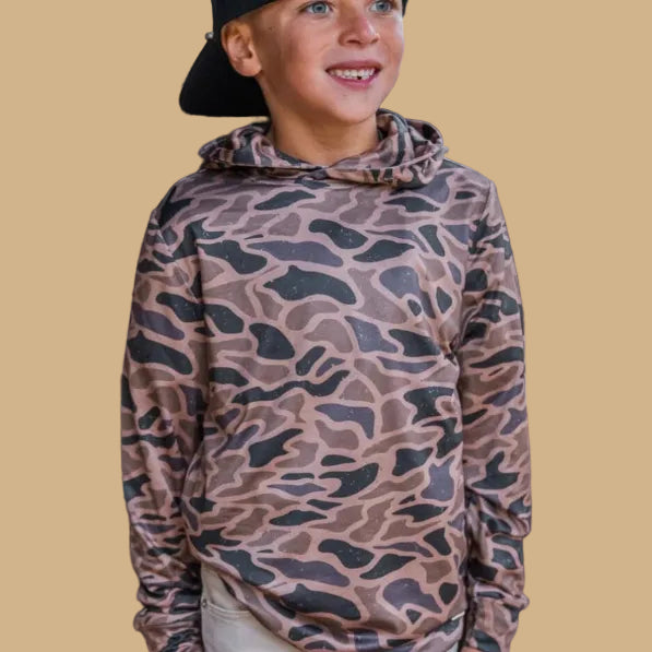 Child wearing a camouflage hoodie on a beige background