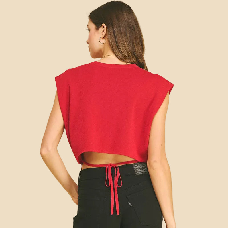 Person wearing a red sleeveless top and black shorts on a beige background