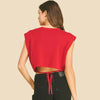 Person wearing a red sleeveless top and black shorts on a beige background