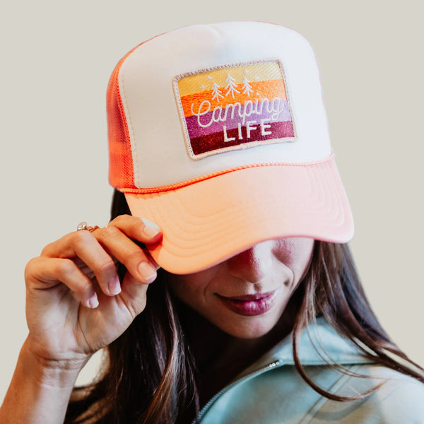 Person wearing a cap with 'Camping Life' patch in an indoor setting