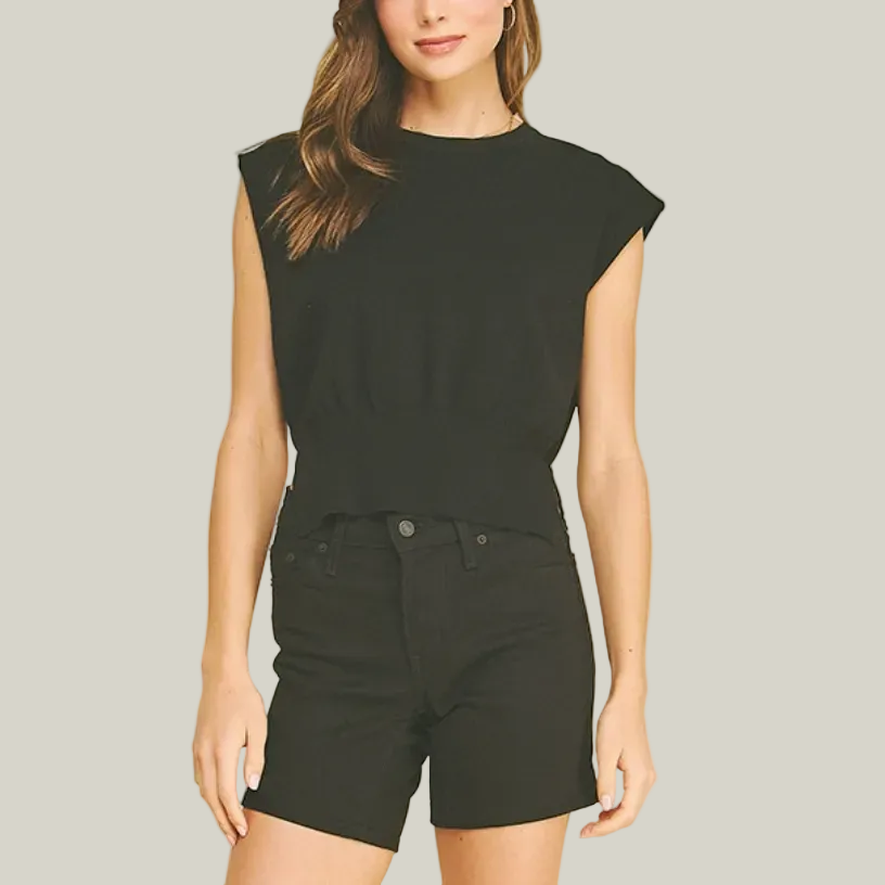 Woman wearing a black sleeveless top and black shorts on a beige background