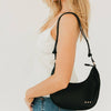 Woman carrying a black handbag on a plain background