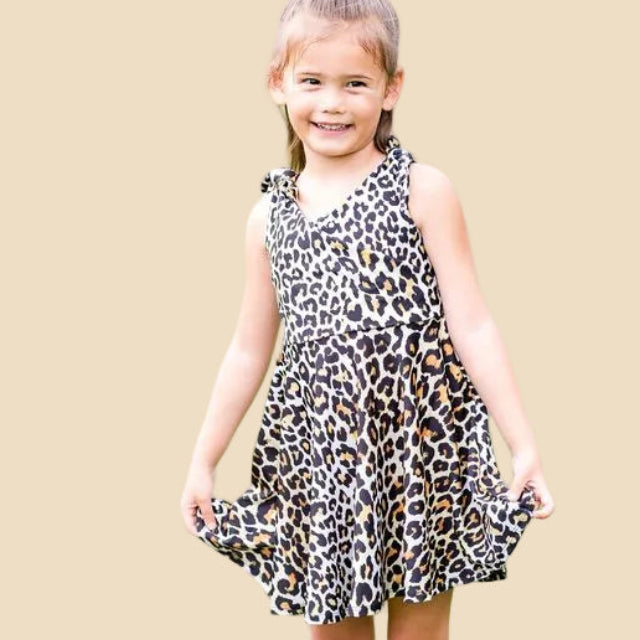 Young girl wearing a leopard print dress against a beige background