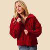 Woman wearing a red knitted cardigan against a beige background