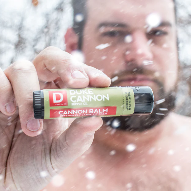 Person holding a Duke Cannon lip balm in a snowy outdoor setting