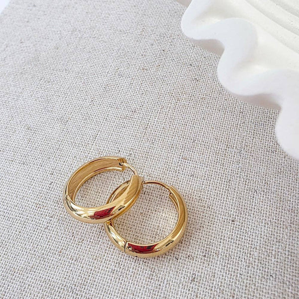 Gold hoop earrings on a textured gray surface