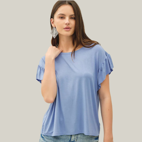 Woman wearing a light blue top with ruffled sleeves against a plain background