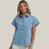 Woman wearing a light blue denim shirt with white patterns on a gray background