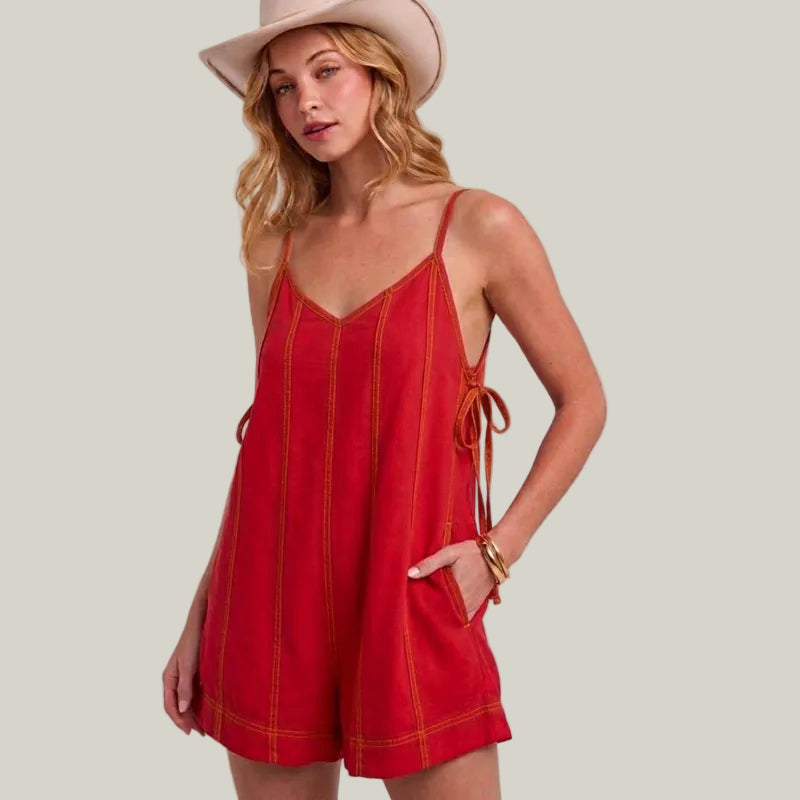 Woman wearing a red dress and beige hat on a plain background