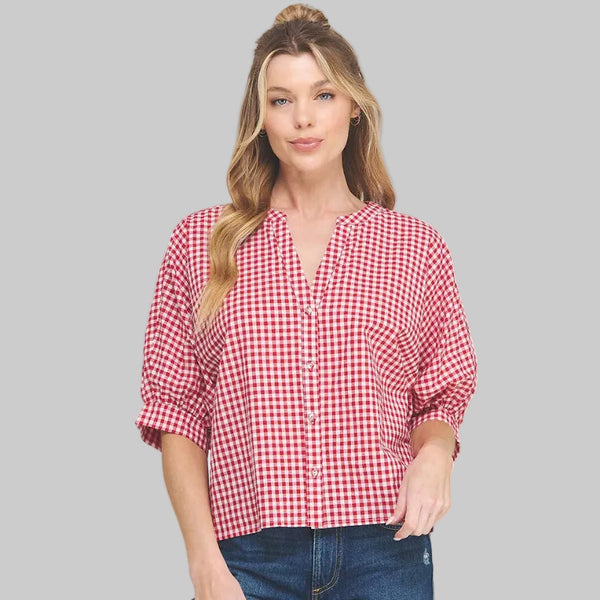 Woman wearing a red and white checkered blouse and blue jeans on a white background