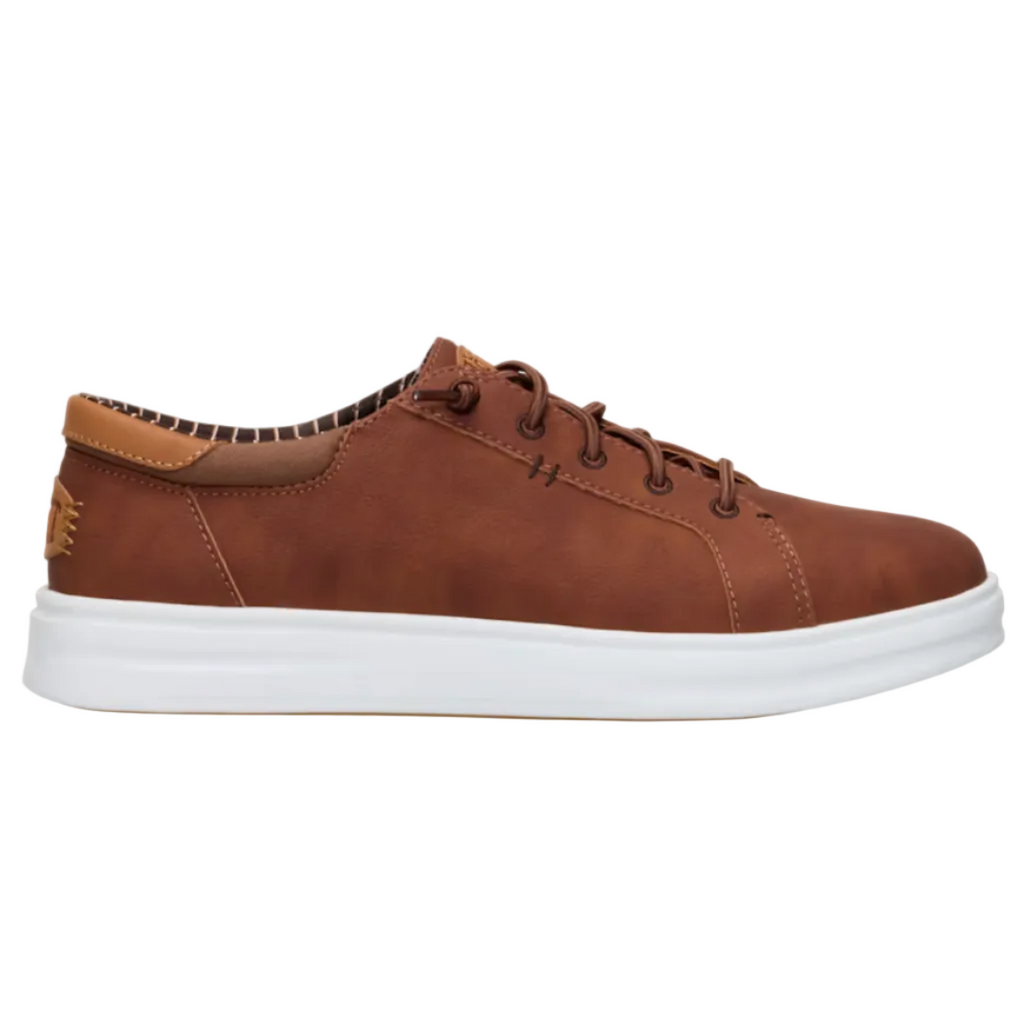 A brown suede low-top sneaker with a thick white rubber sole, shown in a side profile view against a light off-white background.