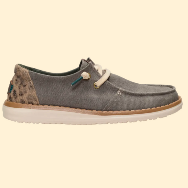 A single casual boat shoe in textured gray suede with a leopard-print heel panel, off-white laces, and a thick off-white sole, shown in profile against a light gray background.
