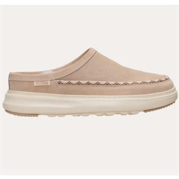 A single slip-on clog-style shoe in a light beige suede-like material with a thick cream sole and a decorative stitched pattern across the vamp, shown against a plain off-white background.