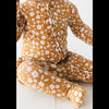 Child wearing a mustard yellow floral outfit on a white background