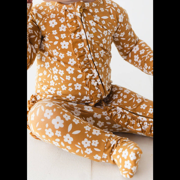 Child wearing a mustard yellow floral outfit on a white background
