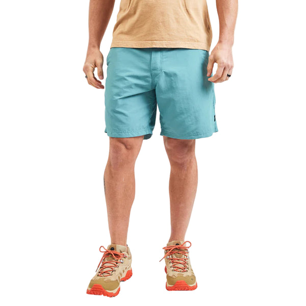 Person wearing light blue shorts and beige shoes on a white background