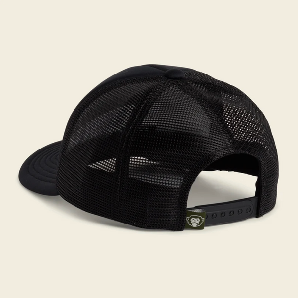 A black trucker-style cap with a black mesh back and a curved black brim, shown from a three-quarters rear angle on a light beige background.