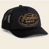 A black trucker hat with a curved brim and black mesh back panels, featuring a gold embroidered logo on the front that reads 'Howler Bros. Austin, TX' with 'Welcome to Howler County' below, set against a light beige background.