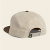 A light beige snapback cap shown from the back, featuring a brown flat brim, brown button on top, and a white plastic adjustment slider with a small black brand patch.