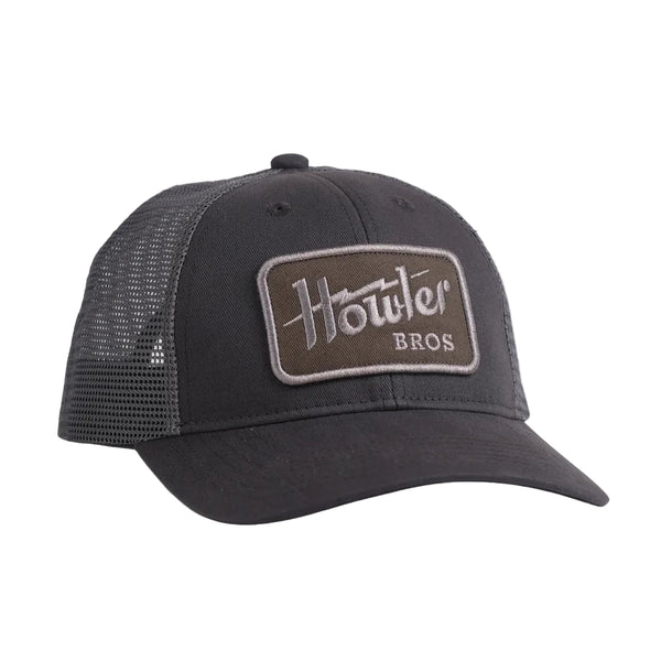 Navy blue trucker hat with a brown patch on a beige background