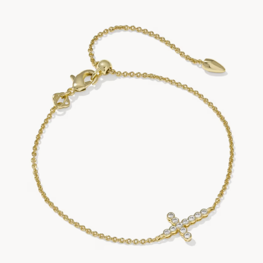 A delicate gold chain bracelet with a small cross charm adorned with clear crystals, displayed on a clean white background.