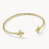 A textured gold cuff bracelet with two small butterfly-shaped closures, each featuring a tiny white inlay, shown on a light gray background.