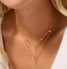 Close-up of a person wearing two gold necklaces with heart pendants.