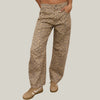 A person wearing loose, wide-leg leopard-print pants with a beige and brown animal pattern, paired with tan sneakers, standing  against a neutral background