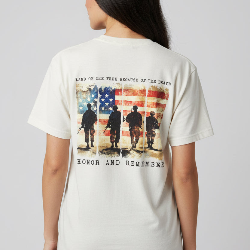 Person wearing a white t-shirt with a graphic design on the back featuring an American flag and silhouettes of soldiers.