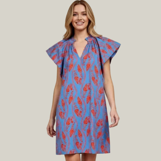 Woman wearing a blue dress with red floral pattern on a beige background