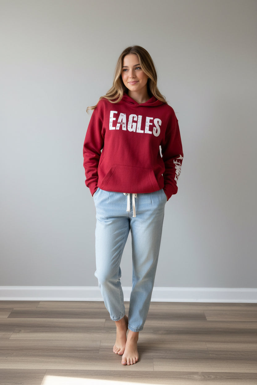 A red pullover hoodie displayed on a mannequin in a clothing store. The hoodie features the word 'EAGLES' in large distressed white letters across the chest and 'LEAKEY' printed vertically in white down one sleeve