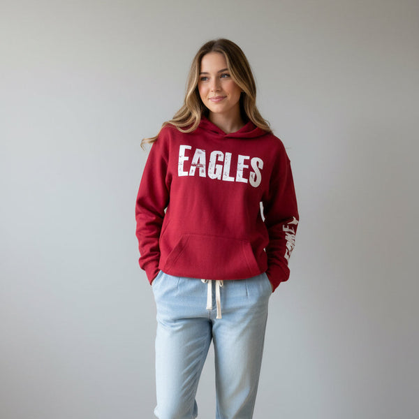 A red pullover hoodie displayed on a mannequin in a clothing store. The hoodie features the word 'EAGLES' in large distressed white letters across the chest and 'LEAKEY' printed vertically in white down one sleeve