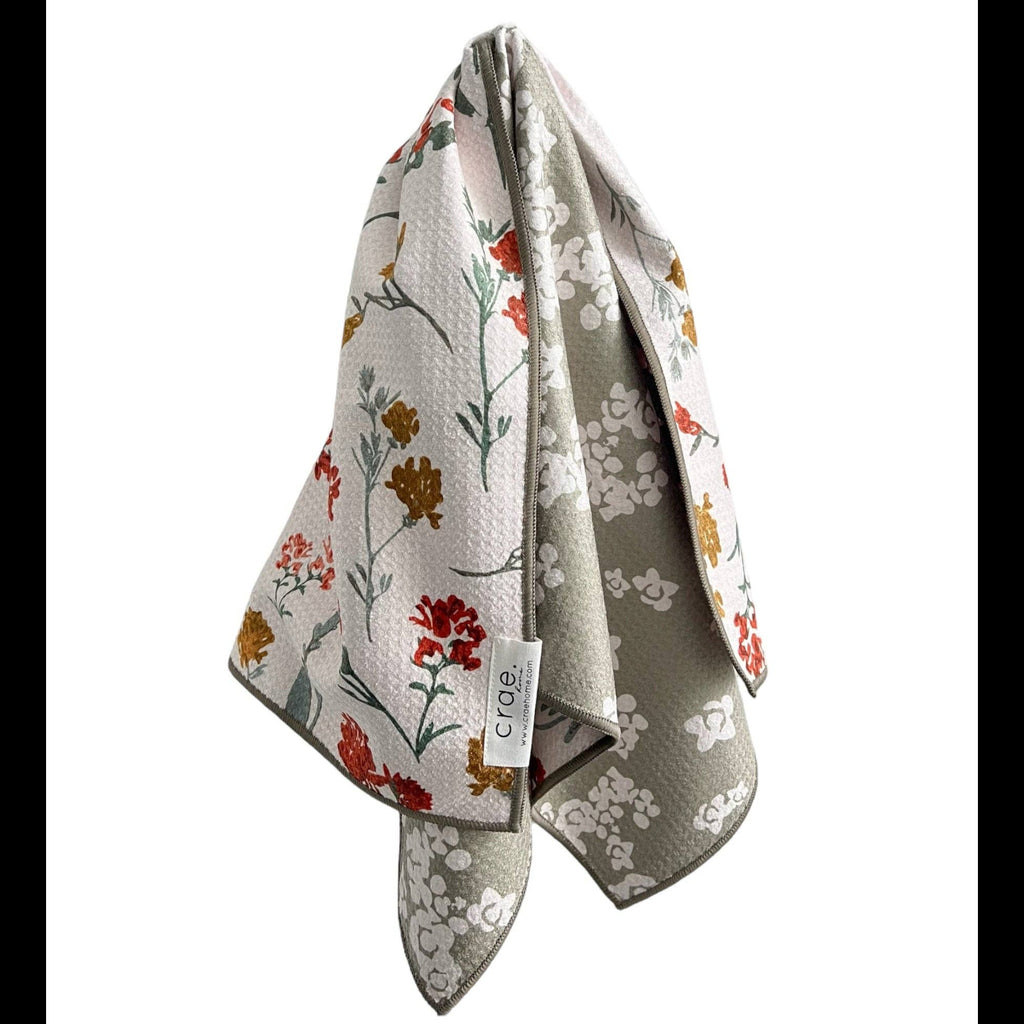 Folded floral patterned towel with a brand tag on a white background