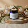 Moo Bueno Skincare jar on a wooden tray with flowers and leaves