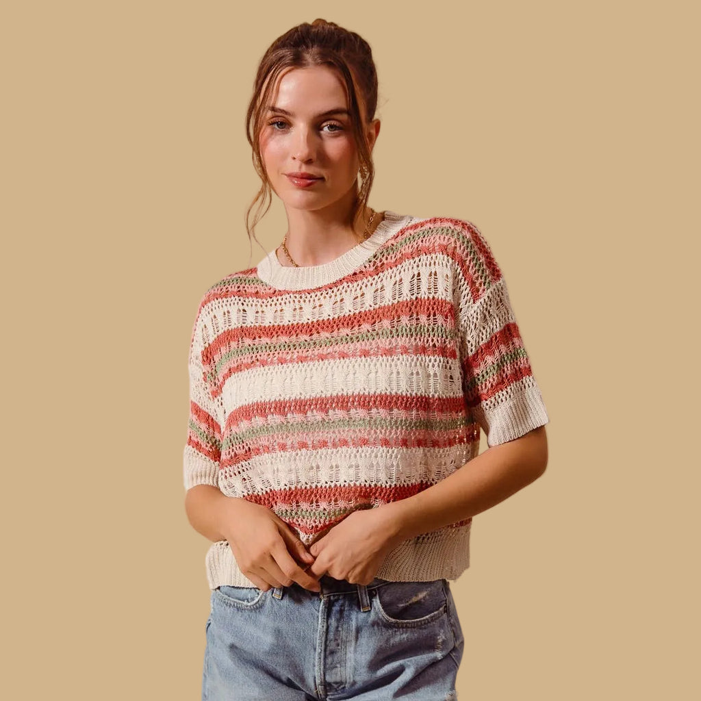 Woman wearing a striped sweater and jeans against a beige background