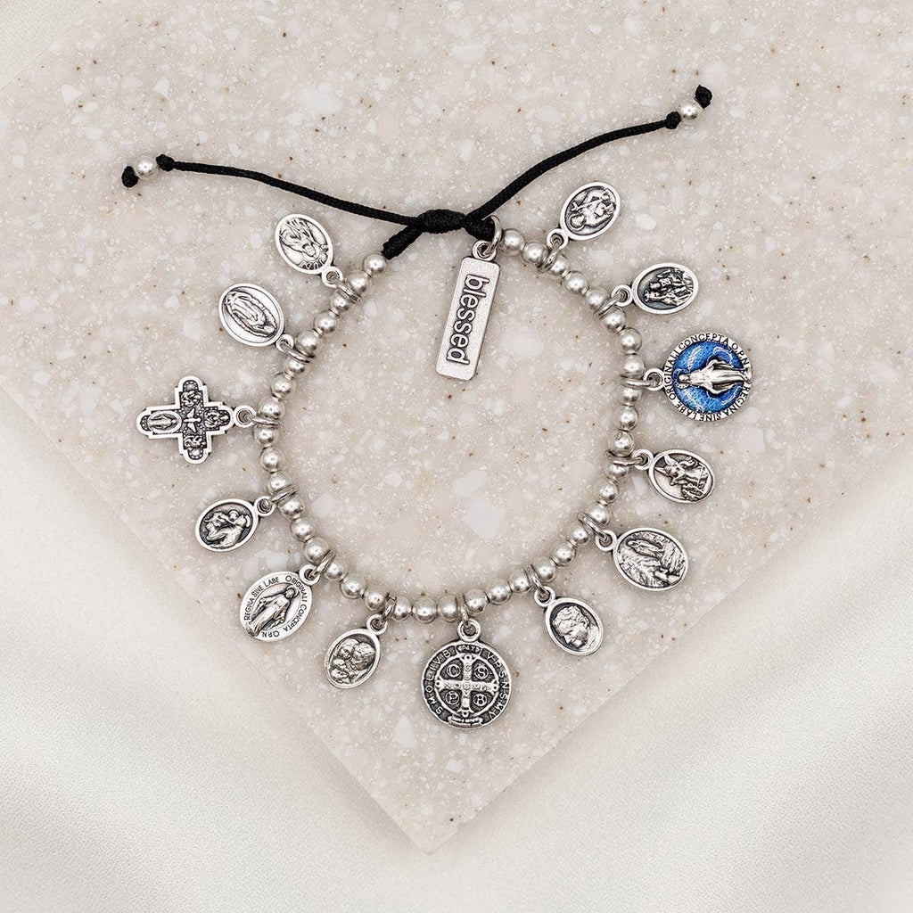 Silver charm bracelet with various charms on a textured surface