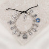 Silver charm bracelet with various charms on a textured surface