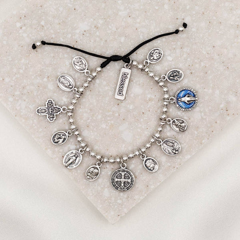 Silver charm bracelet with various charms on a textured surface