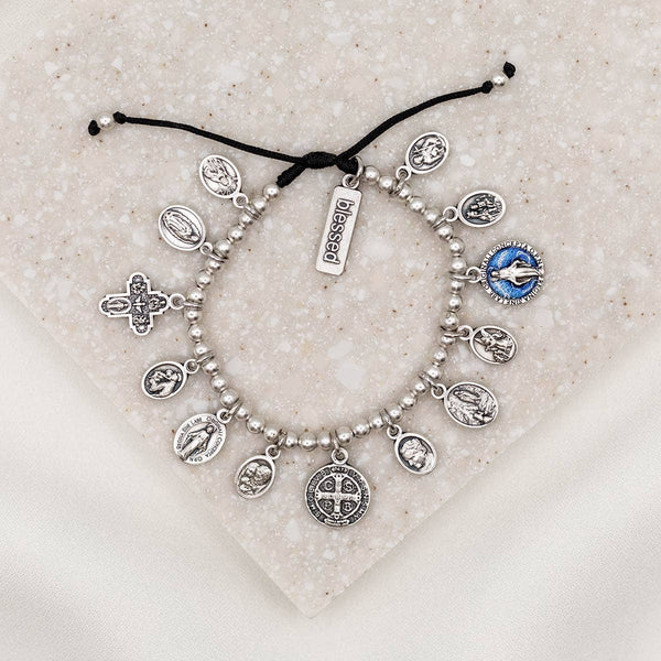Silver charm bracelet with various charms on a textured surface